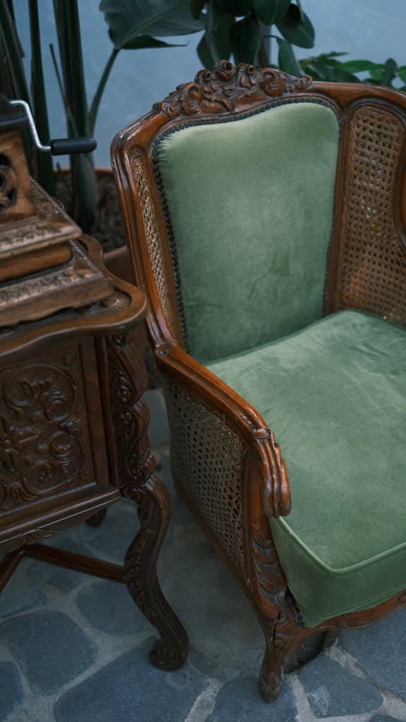 Elegant vintage armchair with green upholstery and ornate wooden detailing indoors.